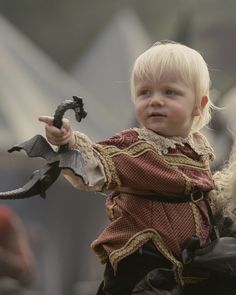 a little boy dressed as a pirate holding a toy bat and wearing a red dress