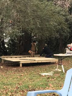 some people are sitting at picnic tables in the woods