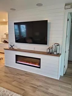 a flat screen tv mounted on the wall above a fireplace in a living room with hardwood floors