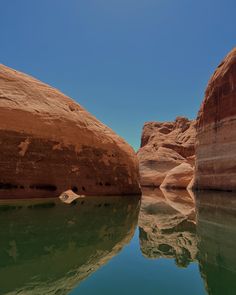 the water is calm and clear in the desert area with large rocks on either side