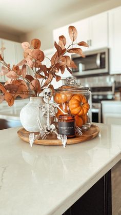 a white kitchen counter top topped with a vase filled with oranges and skeleton figurines