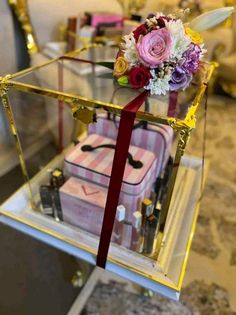 a glass box with flowers and other items in it sitting on a table next to a couch