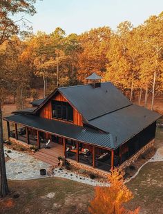 an aerial view of a house surrounded by trees in the fall with leaves on the ground