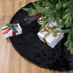 two wrapped presents sitting on top of a black rug next to a christmas tree branch