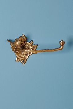 a gold flower shaped hook on a blue wall