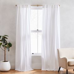 a white chair sitting next to a window in front of a potted plant on top of a hard wood floor