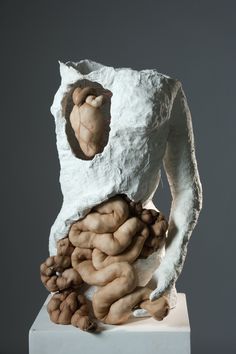 a sculpture made out of clay with hands and fingers on it's back, in front of a gray background