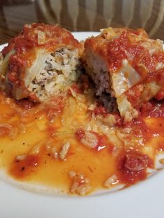 a white plate topped with lasagna and meatballs covered in marinara sauce