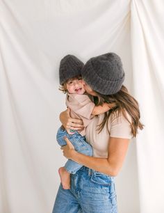 a woman holding a small child in her arms and wearing two hats on their heads