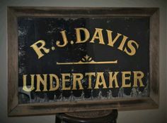 a sign that says r j davis undertaker in gold lettering on a black background