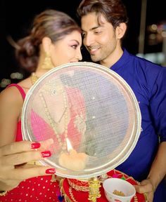 a man and woman standing next to each other holding a plate with a candle in it