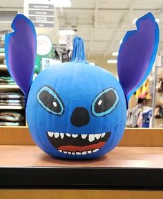 a blue pumpkin with ears and eyes painted on it