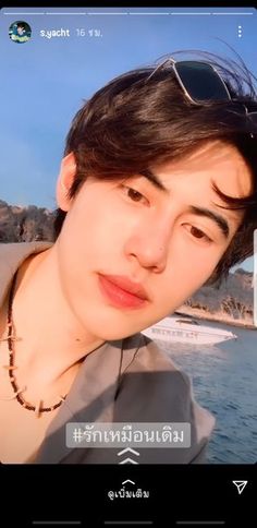 a man with sunglasses on taking a selfie in front of some water and mountains