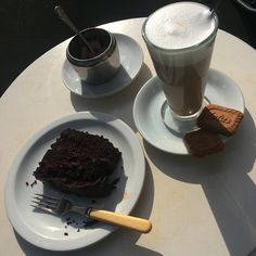 there is a piece of chocolate cake on the plate next to a cup of coffee