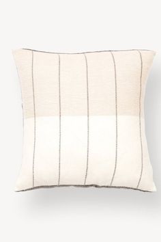 a white pillow with black and grey stripes on it's side, sitting against a wall