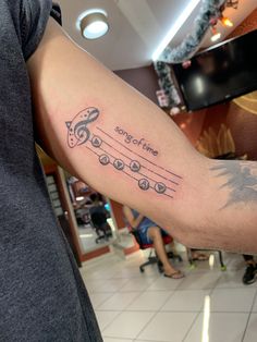 a man's arm with music notes on it and the words song time written in cursive font