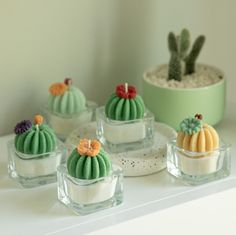 there are many small cakes that look like cacti in glass dishes on the table