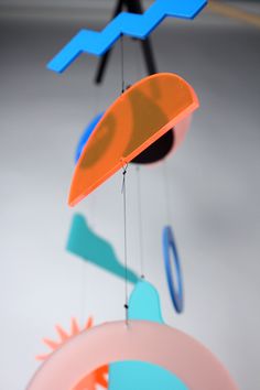 an orange and blue wind chime hanging from a ceiling with other colorful objects on it