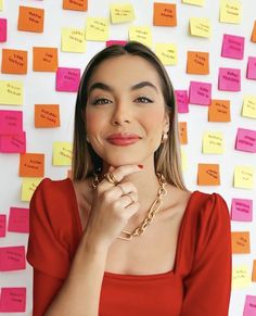 a woman in a red dress posing for a photo with post it notes on the wall behind her