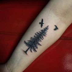 a small pine tree with birds flying around it on the left inner arm tattoo design