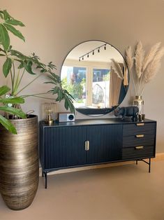 a large mirror sitting on top of a dresser next to a vase filled with plants