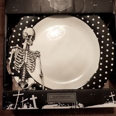 a black and white plate with a skeleton on it in a gift box for halloween