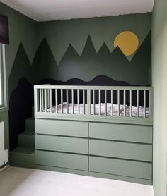 a baby's room with mountains painted on the wall and a crib next to it