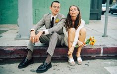 a man and woman sitting next to each other on the sidewalk