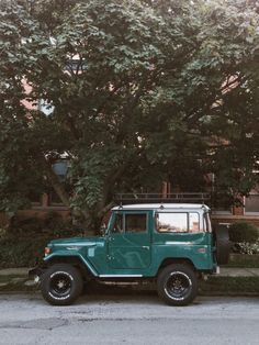 a green jeep parked in front of a tree