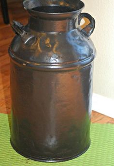 an old metal container sitting on top of a green mat next to a white wall