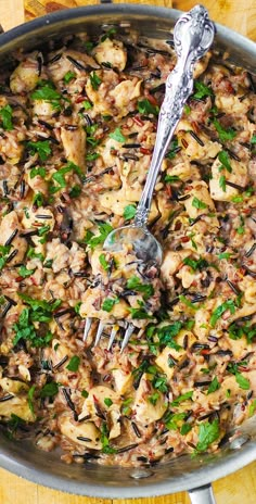 a pan filled with rice and vegetables on top of a wooden table