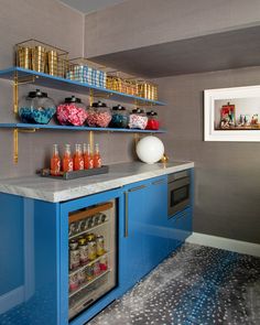 a kitchen with blue cabinets and shelves filled with candy, candies, and drinks