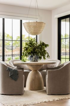 a living room with two chairs and a table in front of large windows that look out onto the yard