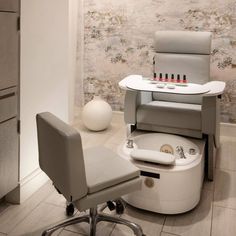 an office chair sitting on top of a white ottoman next to a table with bottles in it