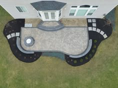 an aerial view of a house with a pool in the front yard and landscaping around it