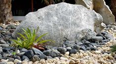 a large rock sitting on top of a pile of rocks next to a planter