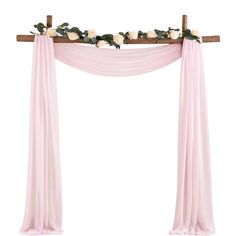 a pink drape with white flowers and greenery on the top is hanging from a wooden cross