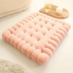 a pink pillow sitting on top of a white table next to a cup and tray