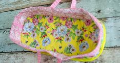 a yellow and pink flowered bag hanging on a wooden wall