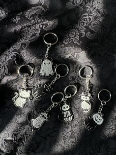 five different key chains are laying on a black and white background with the shadows of halloween characters