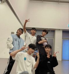 four young men posing for the camera with their hands in the air and one man holding up his peace sign