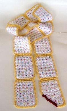 a crocheted scarf is laying on top of a white surface with red, yellow, and blue dots