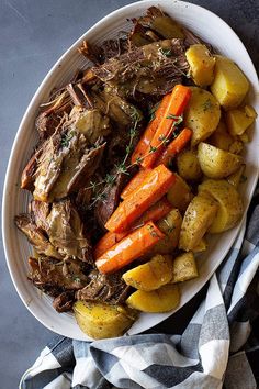 a white plate topped with roast, potatoes and carrots on top of a table