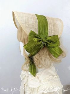 a woman with blonde hair wearing a green bow on top of it's head