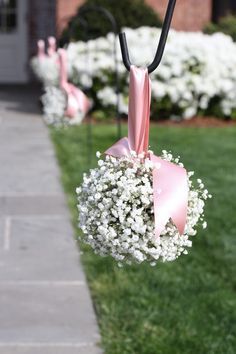 pink ribbon and baby's breath flowers are hanging from an umbrella on the sidewalk