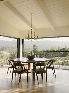 a dining room table with chairs and a chandelier hanging from it's ceiling