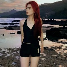 a woman with red hair is standing on the beach