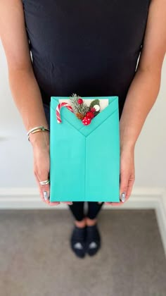 a woman is holding an envelope with candy canes and pine cones in the pocket