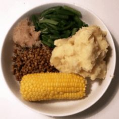 a white plate topped with corn, mashed potatoes and green beans