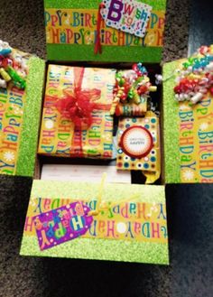 an open gift box on the floor with its contents wrapped in colorful paper and ribbon